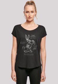 Melns īsām piedurknēm t-krekls ar baltu grafiku, uz kuras attēlots Bugs Bunny un teksts. Mīksts materiāls ar brīvu piegriezumu un noapaļotu kakla izgriezumu.