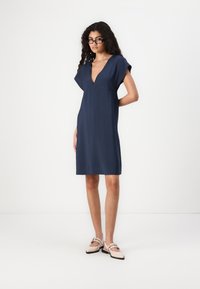 Rochie bleumarin cu decolteu în V, mâneci scurte și croială lejeră. Material moale, neted, cu o lungime până la genunchi și fără modele vizibile.