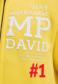 Gelber Pullover mit weißem und rotem Text. Der Text enthält "Stay authentic", "MP DAVID" und "#1" sowie "Rot für Energie", "Gelb für Positivität" und "Blau für Entspannung."
