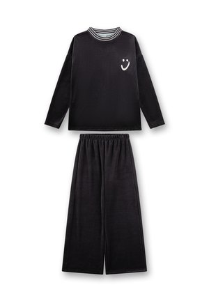 Schwarzes Loungewear-Set mit einem Langarmshirt, das einen gestreiften Kragen und ein Smiley-Gesicht-Graphic aufweist, kombiniert mit weiten Hosen. Weiches Material.