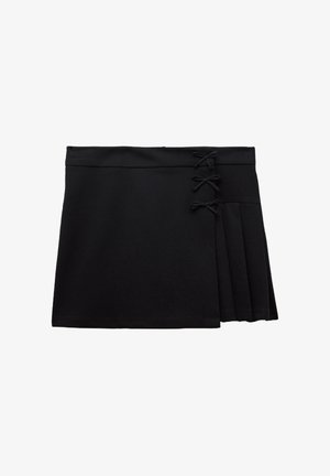 Falda negra con un diseño plisado en un lado, que presenta tres lazos decorativos y una textura de tela suave.