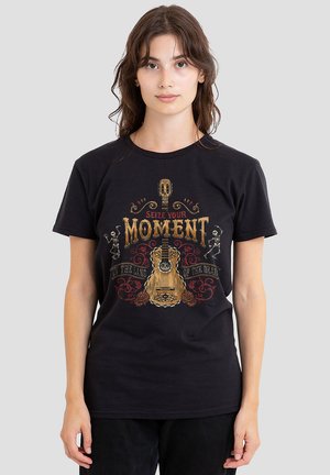 Schwarzes Baumwoll-T-Shirt mit Grafikdesign, das eine Gitarre, Skelette und den Text "Ergreife deinen Moment" in goldenen und roten Akzenten zeigt.