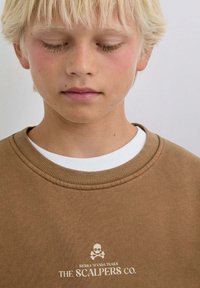 Braunes Sweatshirt mit geripptem Kragen, weißem Innenfutter und Vorderseite mit Grafik eines Totenschädels und dem Text: „SIERRA NEVADA TRAILS THE SCALPERS CO.“