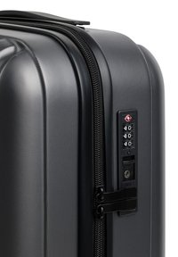 Czarny, twardy walizka w narożniku z podwójnym zamkiem błyskawicznym i wbudowanym zamkiem TSA ustawionym na 000 na białym tle.