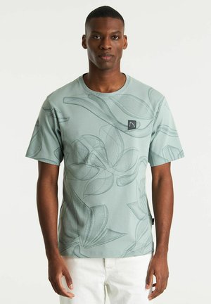 Camiseta de manga corta verde claro con un patrón de hojas dibujado a mano, cuello redondo y un pequeño parche con el logo en el pecho.