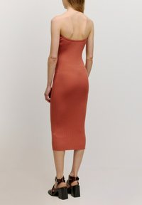 Geribbelde, roestkleurige midi-jurk met een aansluitende silhouet en strapless ontwerp. Heeft een gladde textuur en een lengte onder de knie.