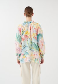 Blusa leggera con motivo floreale in colori pastello, caratterizzata da un colletto a volant e maniche lunghe e ampie. Tessuto in cotone.