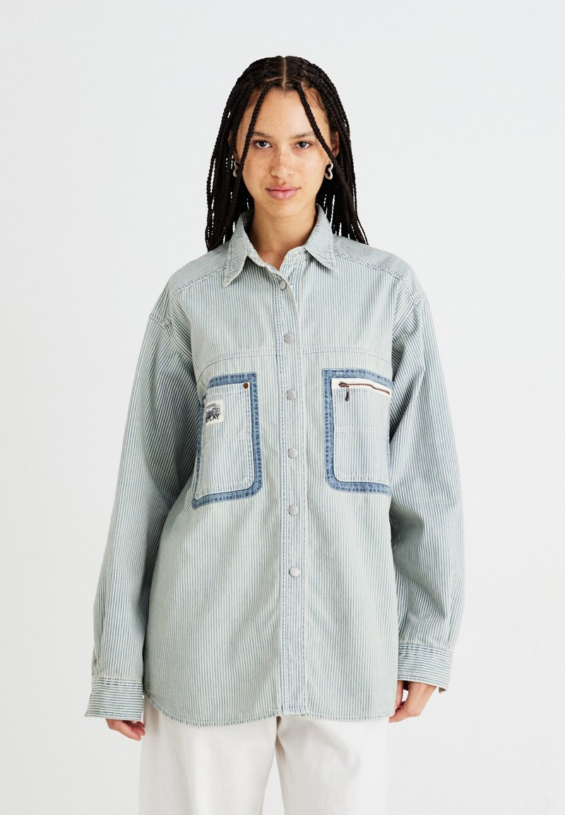 Camicia a righe blu chiaro, design con bottoni, presenta due grandi tasche con dettagli in denim e tessuto testurizzato con vestibilità comoda.