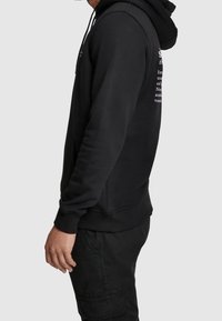 Felpa nera con cappuccio, con tasche frontali e testo sul retro. Materiale: tessuto morbido con polsini e orlo a costine.