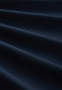Tissu bleu marine foncé avec une texture lisse, présentant des plis doux et un éclat subtil. Le matériau semble léger et flexible.