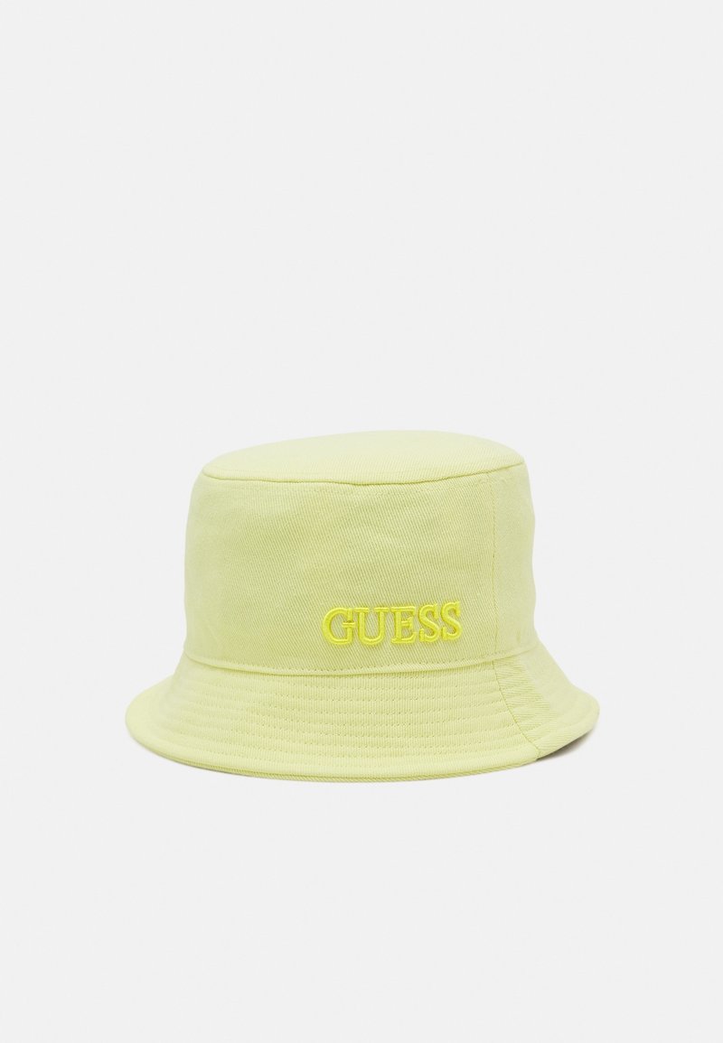 Chapeau seau jaune pâle avec logo "GUESS" brodé en fil jaune assorti, présenté sur un fond clair uni.