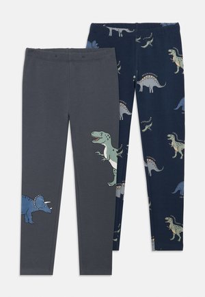 Zwei Paare eng anliegender Leggings; eine graue mit einem blauen Dinosaurier-Graphic, eine dunkelblaue mit mehreren Dinosaurier-Mustern in verschiedenen Farben.