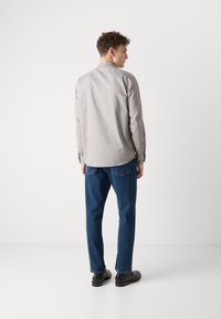 Grå, langermet skjorte med krage. Kombinert med mørkeblå, rette jeans og svarte sko. Enkelt stoffmønster, uformelt design.