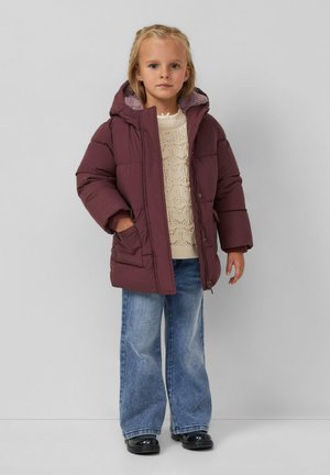 Giacca piumino bordeaux con cappuccio e foderatura pelosa, caratterizzata da proporzioni oversized, abbinata a un maglione lavorato a maglia crema e jeans in denim a gamba larga.