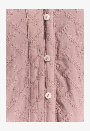 Lyserødt broderet stof med bladmønstre, der har en central knaplukning og struktureret detaljering. Glat, let materiale.