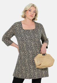 Zwarte en crèmekleurige tuniek met een vierkante halslijn, driekwart mouwen en een aansluitende silhouet, gecombineerd met een gestructureerde strohandtas.
