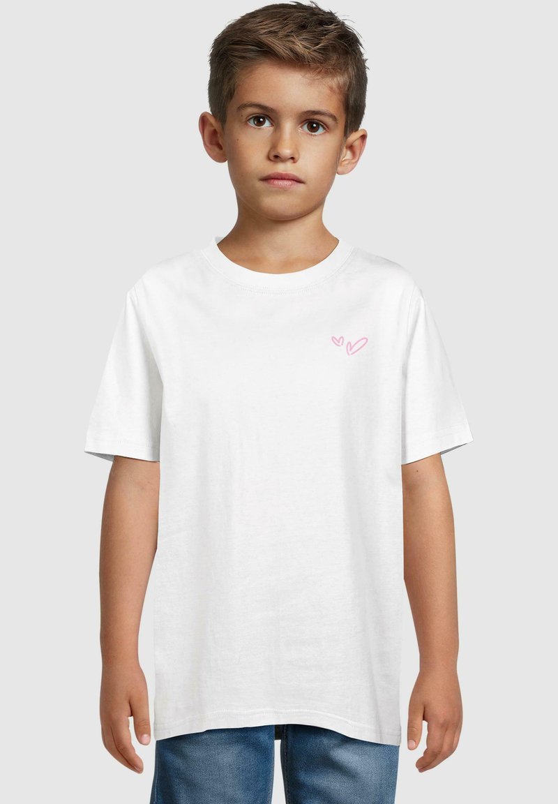 Camiseta de algodón blanca con mangas cortas, que presenta un pequeño gráfico de un corazón rosa en la parte izquierda del pecho. Cuello redondo y corte holgado.