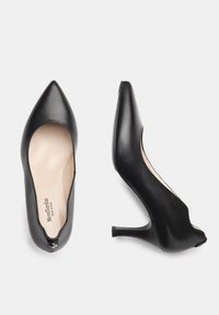 Chaussures à talons hauts en cuir noir avec un bout pointu et un design découpé, dotées d'un petit talon. L'intérieur est revêtu d'une doublure beige et arbore un logo.