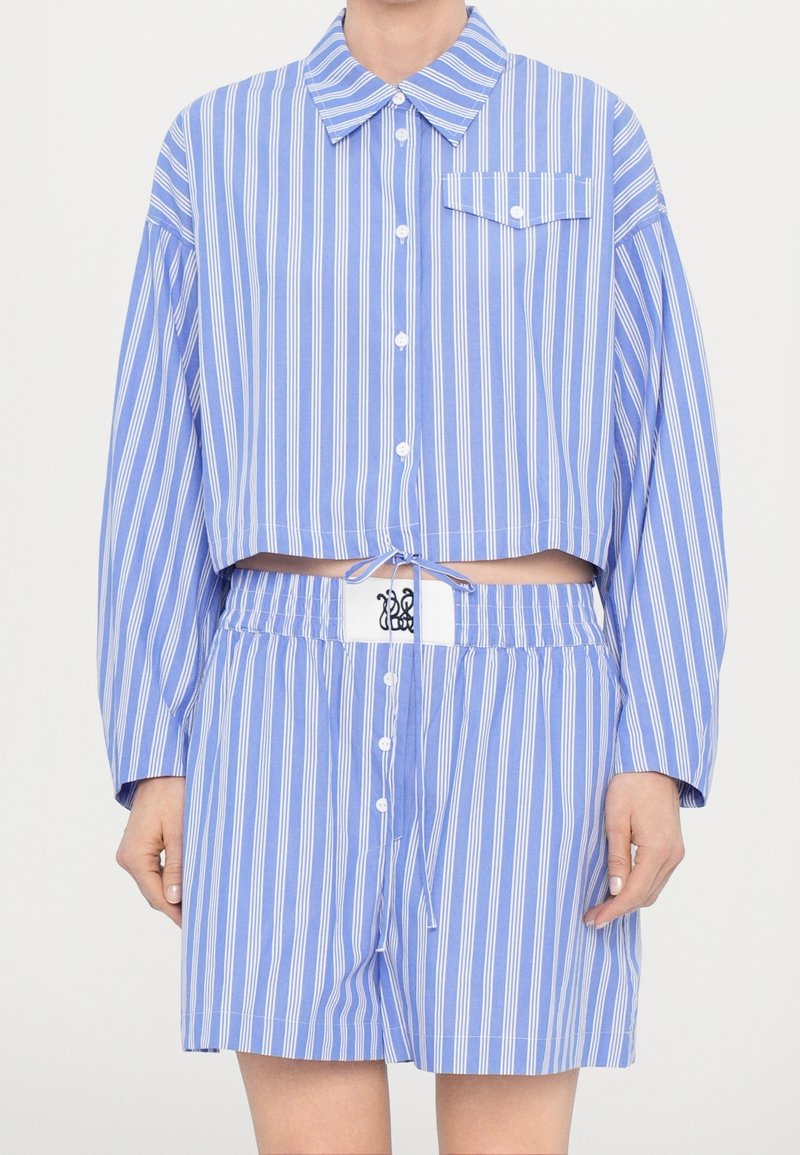Chemise courte rayée bleu et blanc à manches longues avec une poche poitrine, assortie à un short à taille élastique avec logo.
