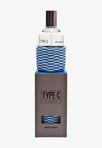 Klar glassparfymeflaske merket "TYPE C" med sølvhette, innpakket i en blå og hvit strikket erme, plassert på en grå "TYPE C" boks.