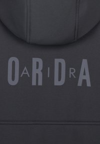 Sweatshirt à capuche noir avec une texture lisse arborant une inscription audacieuse en gris clair "OaRiDra" dans le dos. Design simple et moderne.