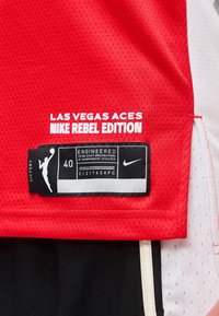 Κόκκινη αθλητική φανέλα με δίχτυ labeled "Las Vegas Aces Nike Rebel Edition" με ετικέτα μεγέθους 40 που διαθέτει σιλουέτα WNBA και λογότυπο Nike.