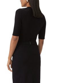 Top en maille noire à manches courtes, avec un col rond et un détail de fermeture éclair au dos, associé à une jupe ajustée assortie.