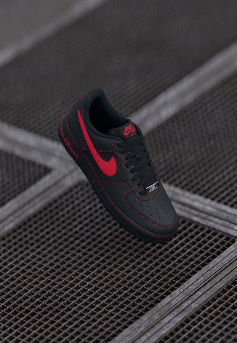 Black leather Nike Air Force 1 sneakers with red accents, featuring a perforated toe, black laces, and a textured rubber sole.