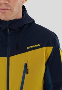 Marineblå og gul lynlåsjakke med hætte, der har en tekstureret overflade, sidelomme og logo på brystet.