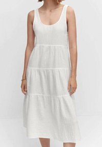 Abito bianco in cotone con scollatura a girocollo, design senza maniche, volant a strati e una finitura leggermente testurizzata. Lunghezza al ginocchio. Accenti semplici.