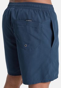 Μπλε ναυτικό μαγιό σορτς κατασκευασμένο από ελαφρύ ύφασμα με ελαστική μέση. Διαθέτει πίσω τσέπη με μεταλλικό κρίκο και ετικέτα με λογότυπο.