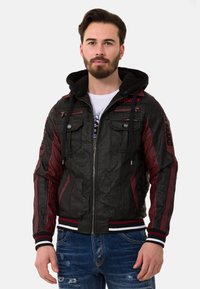 Lederjacke mit einer strukturierten schwarzen Oberfläche, burgunderfarbenen Akzenten, einem Reißverschluss vorne und einer Kapuze. Enthält mehrere gefütterte Taschen mit Reißverschluss und gestreifte Bündchen.