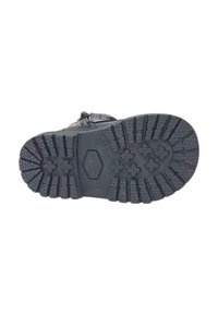 Suola di scarpa in gomma nera con superficie testurizzata. Presenta scanalature profonde per una buona aderenza e un logo esagonale vicino al centro.