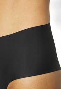Black seamless underwear with a smooth, stretchy fabric. Features a wide band at the top and a mid-rise cut for comfort.