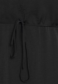 Zwarte stof met een gladde textuur, voorzien van een strikdetail in de taille en een losse, gedrapeerde ontwerp.