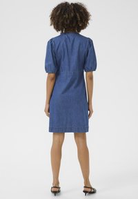 Denim dress with short puff sleeves, a fitted waist, and a straight cut. Finished with contrast stitching and a knee-length hem.