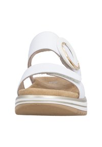 Sandale blanche à deux brides, dont l'une ornée d'une boucle circulaire décorative en or et blanc, avec une semelle intérieure rembourrée beige.