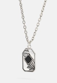 Colar de corrente em prata com um pingente octogonal, apresentando uma pedra negra e padrões de folhas gravados. Acabamento texturizado com detalhes nas bordas.