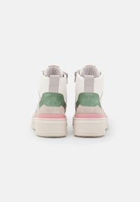 High-top sneakers with a white leather upper, green and pink suede accents, and a chunky white sole. Zip closure at the back.