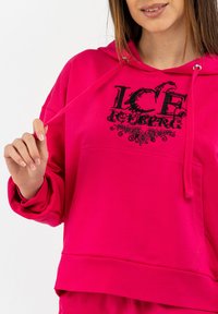 Felpa con cappuccio fucsia, dotata di tasca frontale e dettagli grafici neri con il logo "ICEBERG". Tessuto morbido e polsini a coste.
