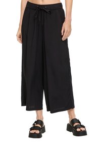 Zwarte wijde broek met een elastische tailleband en trekkoord, voorzien van een zachte stof en zijsplits voor extra detail.