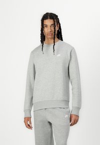 Sivi Nike dukserica sa okruglim izrezom, rebrastim manžetama i porubu, sa malim bijelim logotipom na lijevoj strani prsnog koša. Mekana tekstura i ležeran kroj.