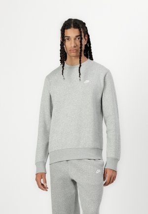 Sweatshirt Nike gris avec un col rond, des poignets et un ourlet côtelés, présentant un petit logo blanc sur la poitrine gauche. Texture douce et coupe décontractée.