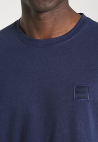 T-shirt di cotone blu navy con scollo tondo e piccolo logo quadrato ricamato a tono sul petto a sinistra.