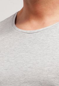 Tricou gri din bumbac, cu o textură fină, guler rotund și mâneci scurte, evidențiat de un model subtil heather.