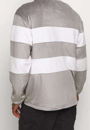 Camiseta de manga larga gris con rayas blancas horizontales. Textura suave con un diseño casual, escote redondeado y corte relajado.