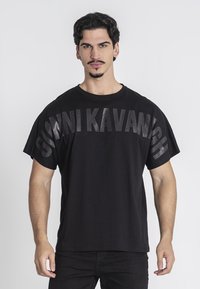 Camiseta negra de algodón, con silueta oversize y texto en negrita "GIOVNI KAVANIGH" impreso en la parte frontal con un acabado mate.