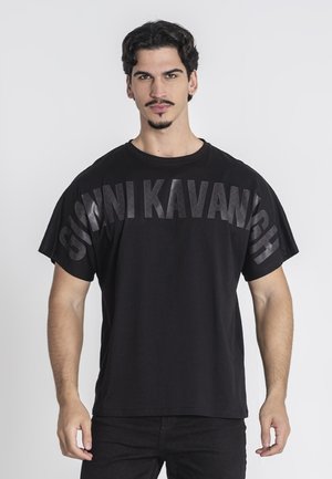 Camiseta negra de algodón, con silueta oversize y texto en negrita "GIOVNI KAVANIGH" impreso en la parte frontal con un acabado mate.
