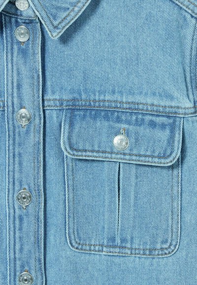 Giacca di jeans azzurra chiara con bottoni a pressione in argento, una tasca sul petto e cuciture in evidenza. La texture è liscia con una leggera lucentezza.