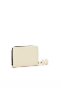 Cartera con cremallera de color crema, con una textura suave y esquinas redondeadas; cuenta con un charm en forma de oso sujeto a la cremallera.